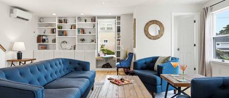 A modern living room with a sectional sofa, a wooden coffee table, and a bookshelf filled with books and decorative items.