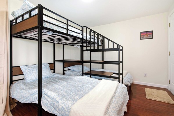Habitación con literas de madera, ropa de cama estampada y una alfombra pequeña en el suelo.