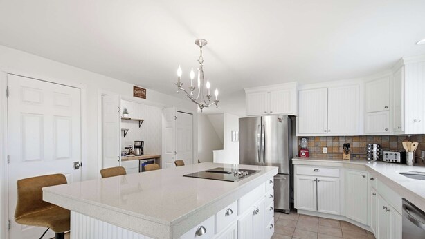A modern kitchen with white cabinetry, a stainless steel refrigerator, and a central island. - Waterfront - Sauna -steps To Beach! (Saco)