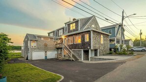 A two-story house with a garage, a covered porch, and a staircase leading to the upper level. - Waterfront - Sauna -steps To Beach! (Saco)