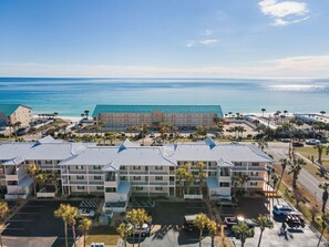 A beachfront hotel with multiple buildings, parking areas, and a view of the ocean. - Thousand Sunnies (Destin)