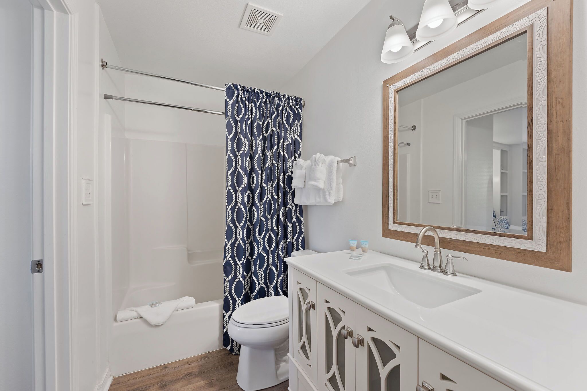 A bathroom with a shower, toilet, and vanity with a mirror.