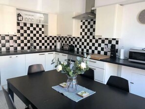 A modern kitchen with white cabinets, a black and white checkered backsplash, and a dining table with chairs. - Spacious 3-Bed Apartment in Queen's Quarter (Belfast)