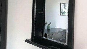 A wall-mounted mirror with a black frame and a shelf below it. - Spacious 3-Bed Apartment in Queen's Quarter (Belfast)