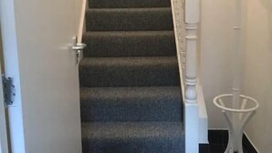 A carpeted staircase with a white handrail and a coat stand to the right. - Spacious 3-Bed Apartment in Queen's Quarter (Belfast)