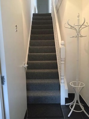 A carpeted staircase with a white handrail and a coat stand to the right. - Spacious 3-Bed Apartment in Queen's Quarter (Belfast)