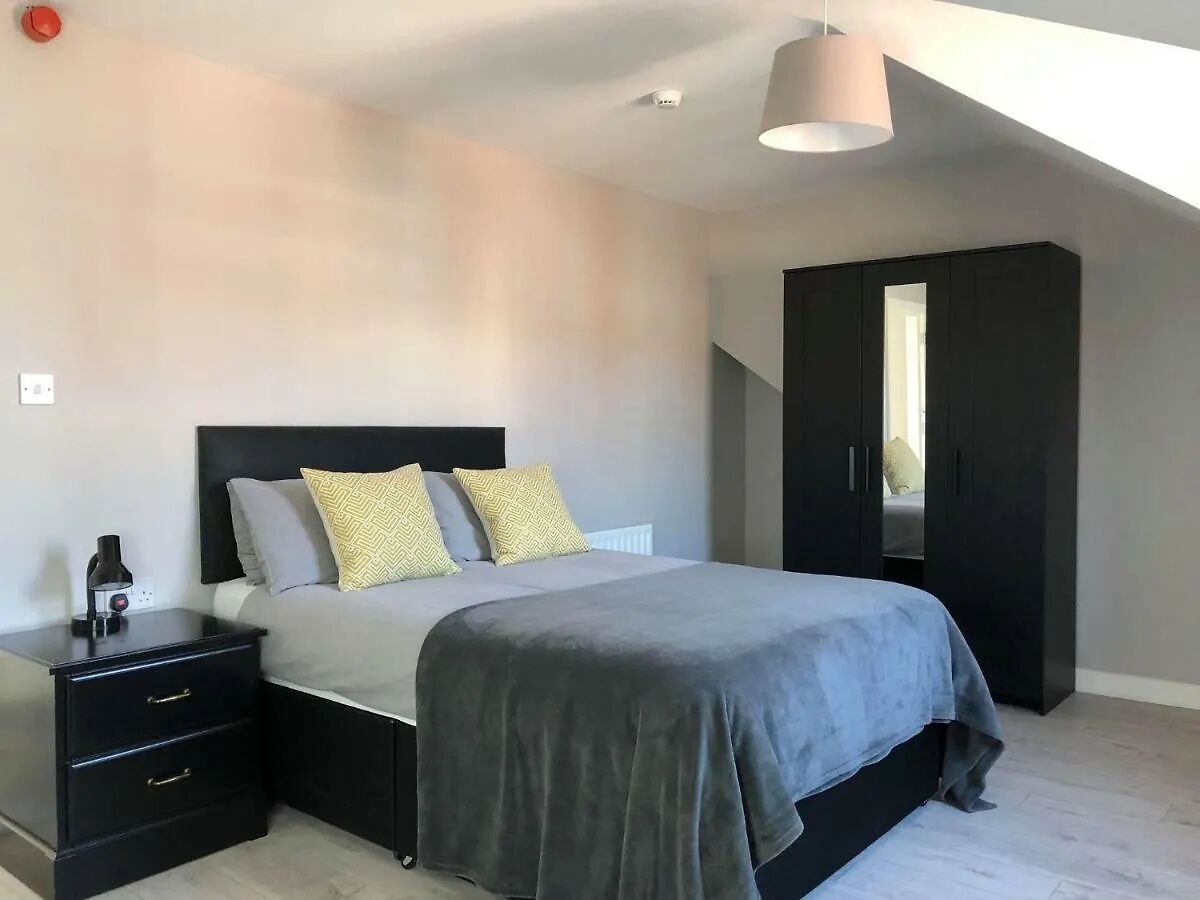 A bedroom with a bed, bedside tables, a wardrobe, and a ceiling light fixture.