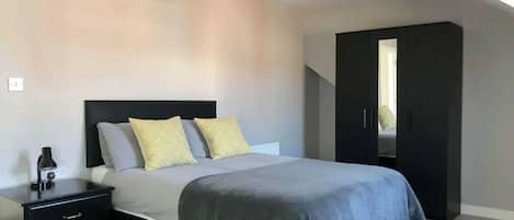 A bedroom with a bed, bedside tables, a wardrobe, and a ceiling light fixture.