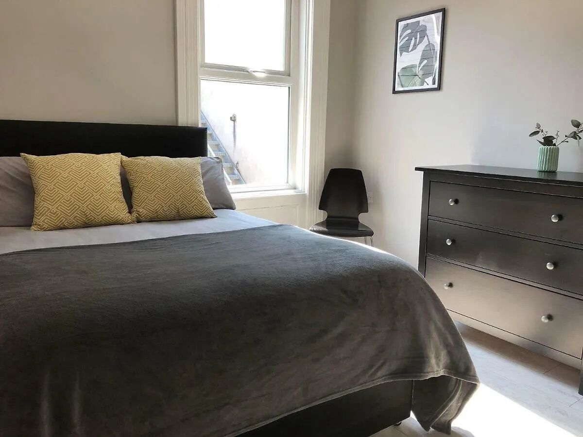 Een slaapkamer met een bed, een kaptafel, een raam en een lijst met een afbeelding aan de muur.