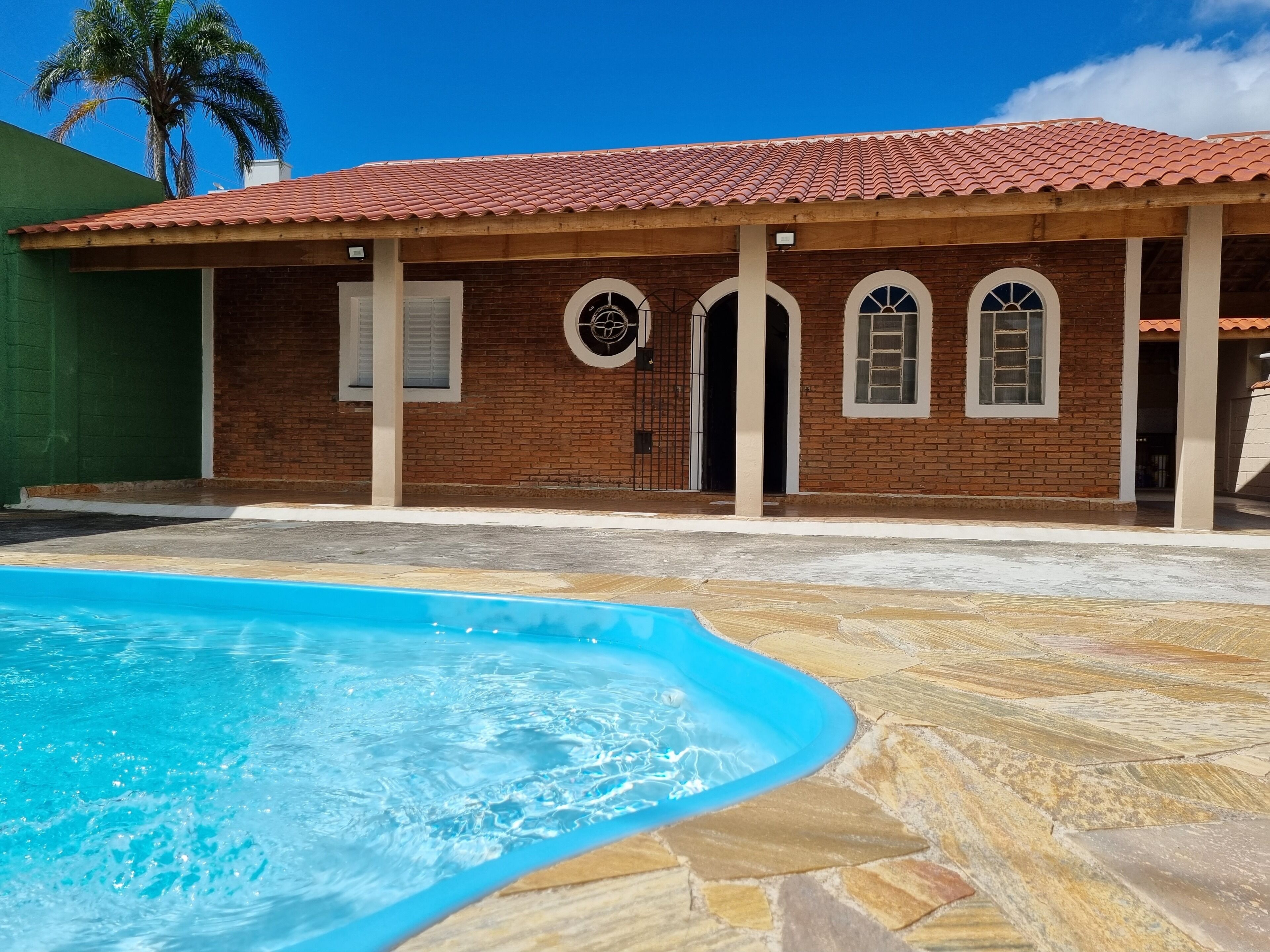 Ein Haus mit Swimmingpool, Ziegelhaus und einem gefliesen Dach.