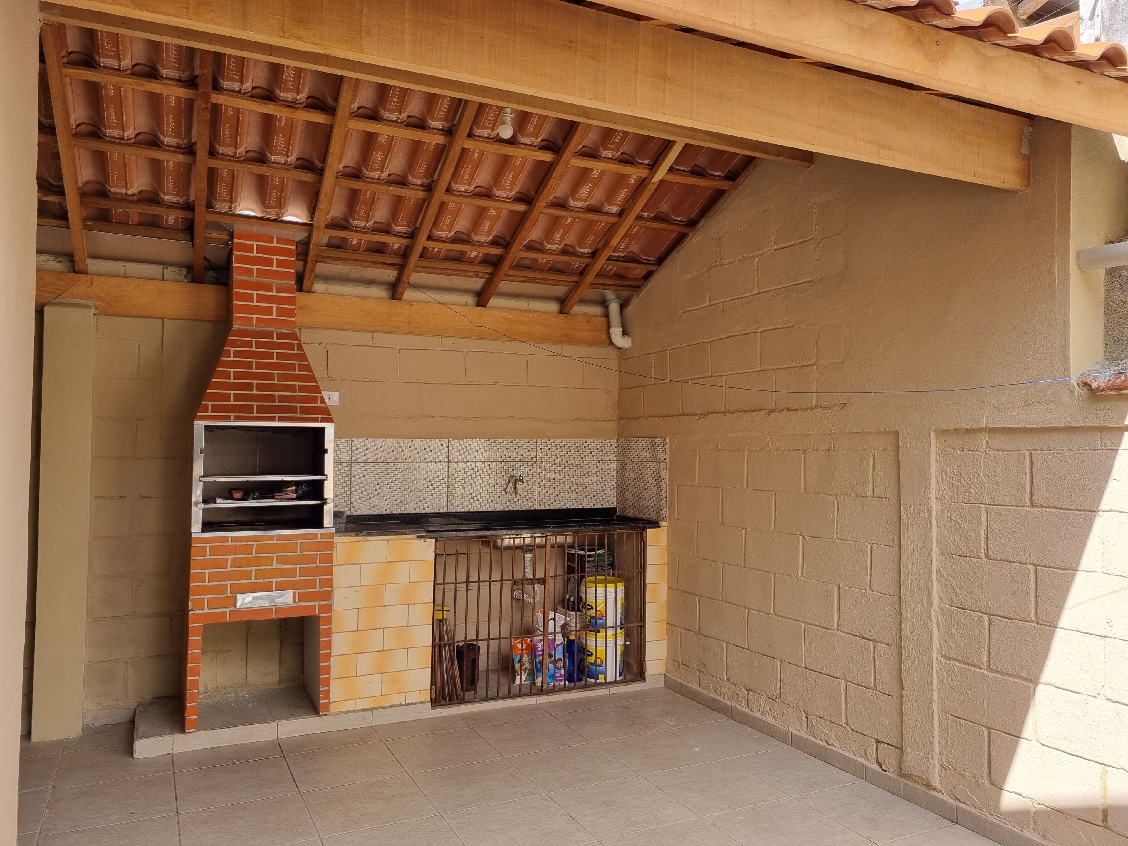 A brick-built outdoor kitchen with a chimney, a tiled backsplash, and a metal grill enclosure.