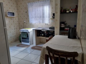 Cocina compacta con microondas, horno, lavamanos y una zona de comedor con mesa y sillas.