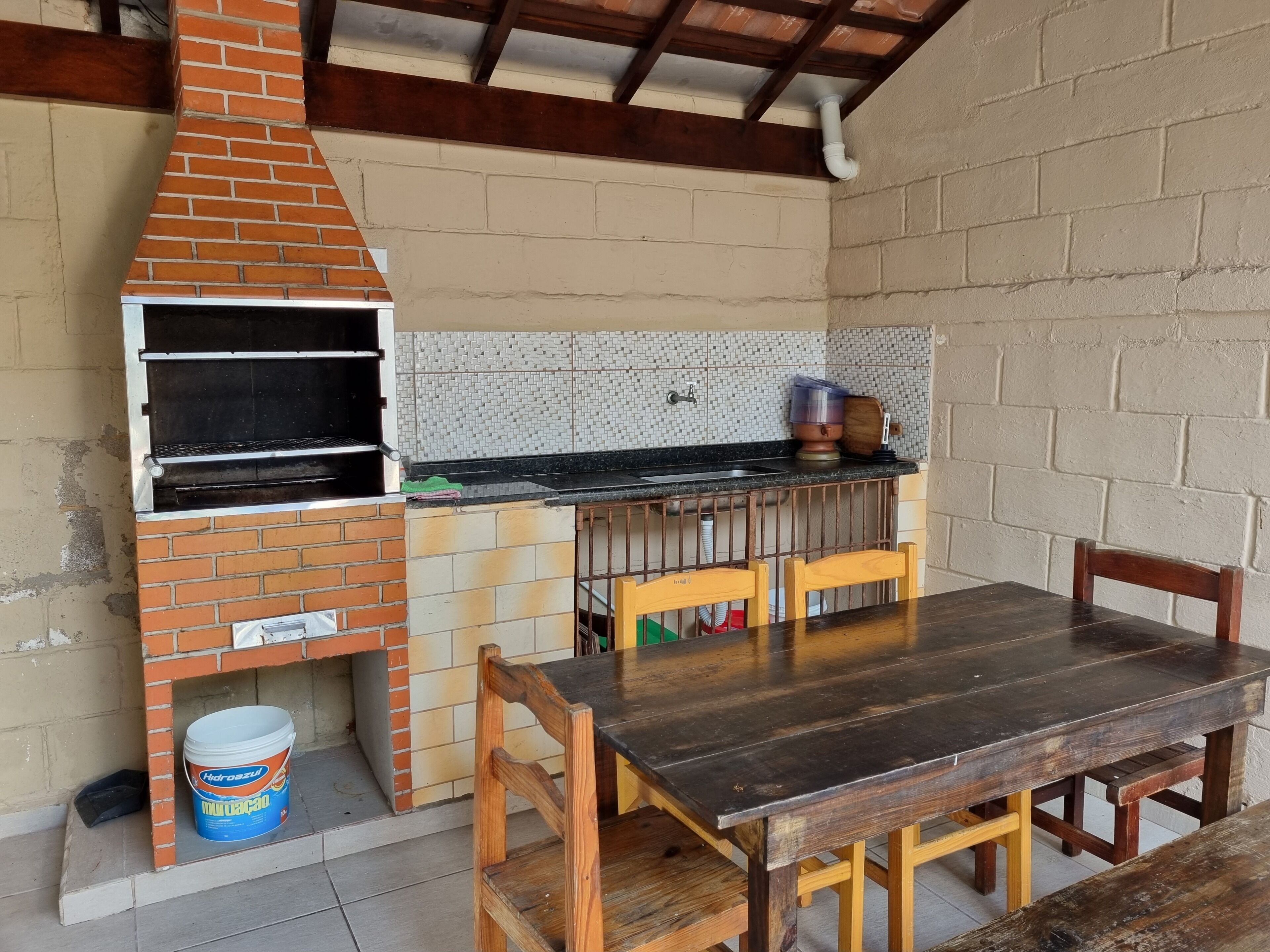 Une cuisine équipée d’un four en briques, d’un évier et d’une table à manger avec des chaises.