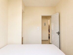 Un dormitorio con cama, una puerta que da a un pasillo y un armario con puertas correderas.