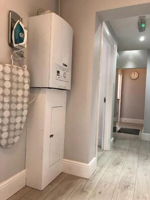 A hallway with a white appliance, a wall-mounted device, and a patterned object. - Stylish 2 BR Queens Quarter Ground Floor Apartment (Belfast)