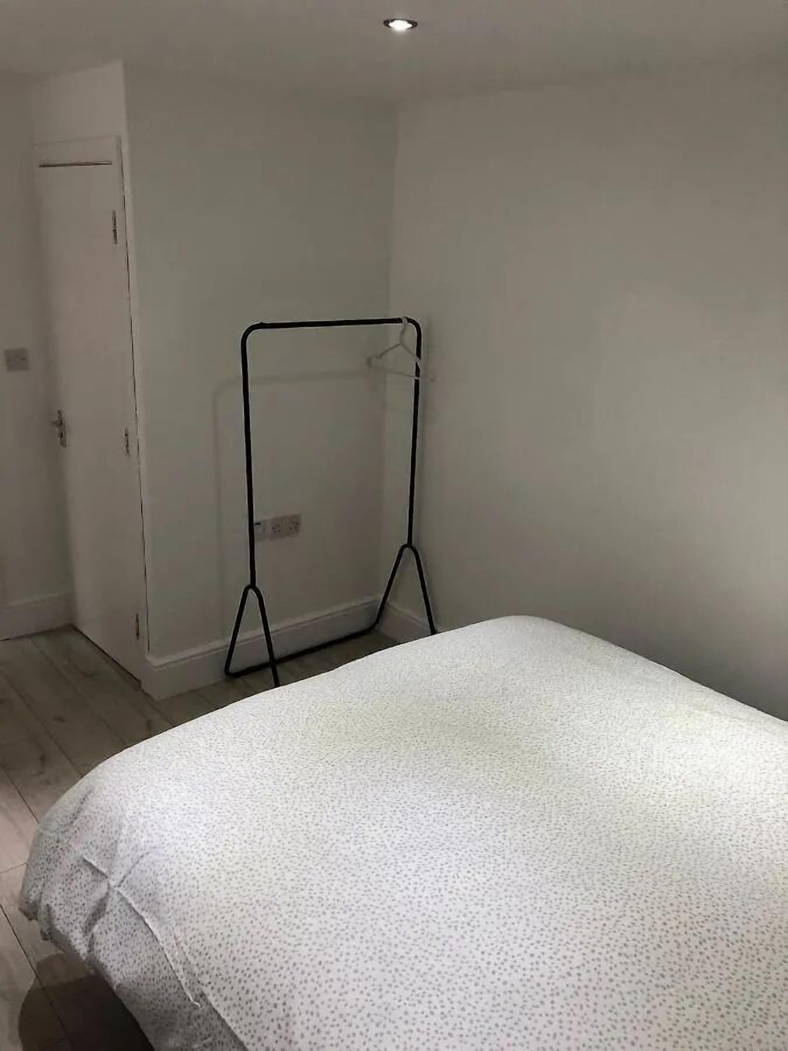 A bedroom with a bed, a white door, and a black metal stand.