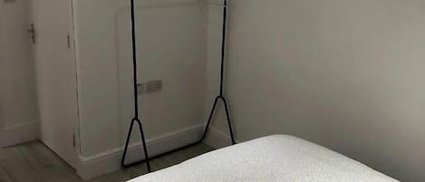 A bedroom with a bed, a white door, and a black metal stand.