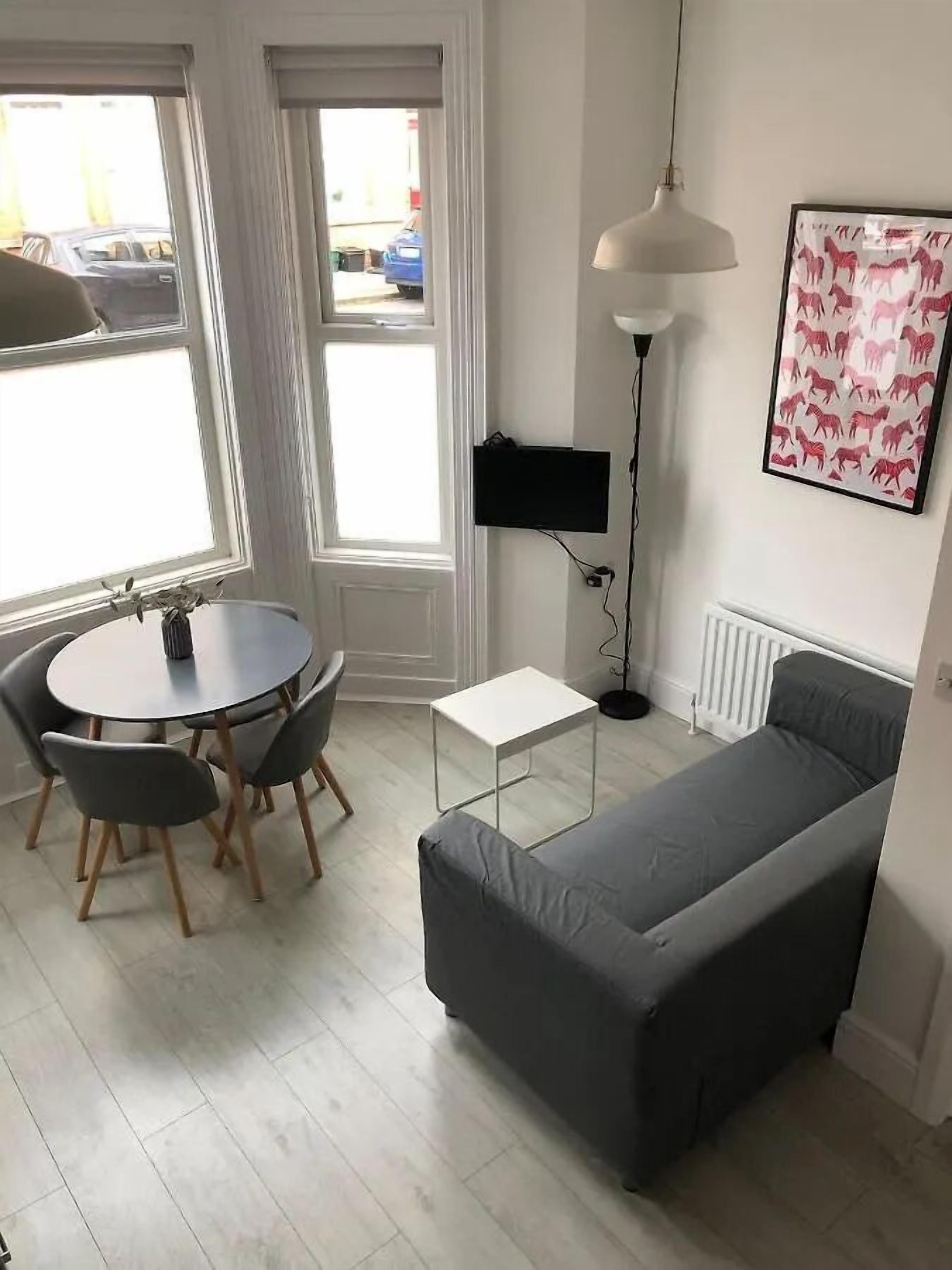 Ein gemütlicher Wohnraum mit Esstisch, Sofa, Stehlampe und Heizkörper.