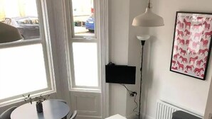 Kompakti olohuone, jossa on ruokapöytä, sohva, lattiavalaisin ja patteri.