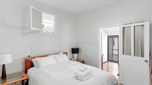 A hotel room with a bed, bedside tables, a lamp, a mirror, and a door leading to a balcony.