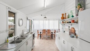 A compact kitchen with a dining area, white cabinetry, and a large window.