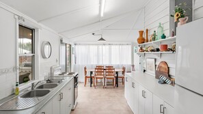 A compact kitchen with a dining area, white cabinetry, and a large window.