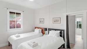 A hotel room with two beds, a window, and a door leading to a balcony.