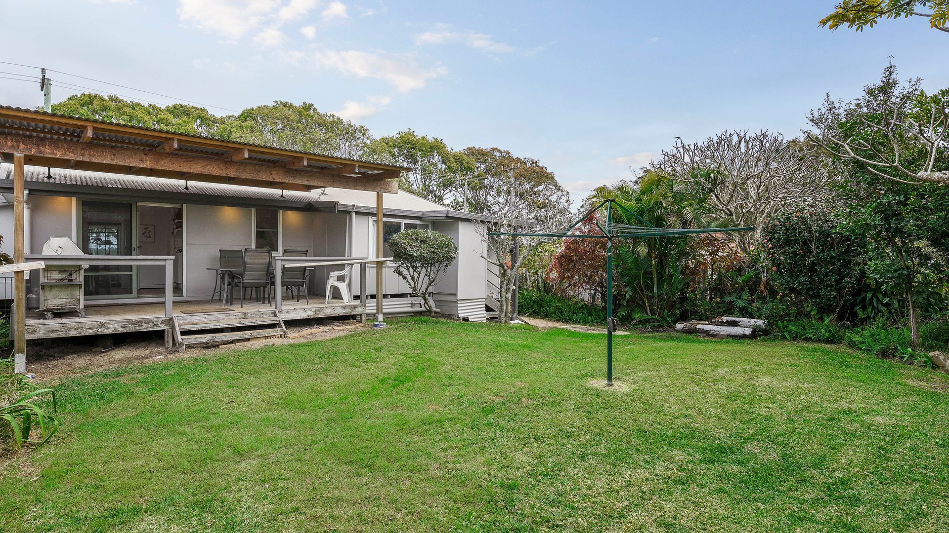 Ein Wohnhaus mit überdachter Terrasse, Sitzgelegenheiten im Freien und einem gepflegten Rasen.