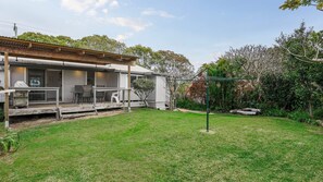 A residential property with a covered patio, outdoor seating, and a well-maintained lawn.
