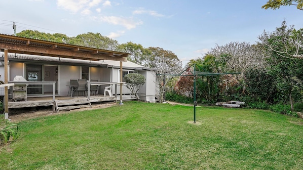 A residential property with a covered patio, outdoor seating, and a well-maintained lawn.