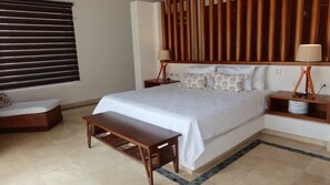 A bedroom with a large bed, bedside tables, a bench, and a wooden headboard. - Caribbean Bungallow With 2 Bedrooms in Cap Cana (Punta Cana)