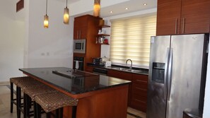 A kitchen with a central island, stainless steel appliances, and wooden cabinetry. - Caribbean Bungallow With 2 Bedrooms in Cap Cana (Punta Cana)