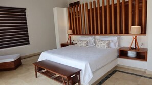 A hotel room with a large bed, bedside tables, a bench, and a wooden headboard. - Caribbean Bungallow With 2 Bedrooms in Cap Cana (Punta Cana)