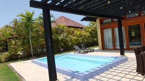 A swimming pool with a tiled edge, surrounded by a patio area with lounge chairs. - Caribbean Bungallow With 2 Bedrooms in Cap Cana (Punta Cana)