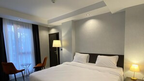 A hotel room with a large bed, two chairs, a small table, and a lamp. - Armada Hotel (İstanbul)
