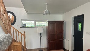 Ein Wohnzimmer mit Treppe, einem Holzschrank, einer Lampe und einem schwarzen Tisch.