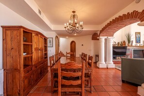 A dining room with a large wooden table, chairs, a chandelier, a fireplace, and a spiral staircase. - Hacienda Almas Gemelas – Where Luxury Meets the Sea of Cortez (Puerto Peñasco)