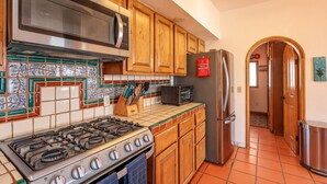 A kitchen with a gas stove, microwave, refrigerator, and wooden cabinets. - Hacienda Almas Gemelas – Where Luxury Meets the Sea of Cortez (Puerto Peñasco)