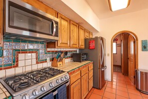 A kitchen with a gas stove, microwave, refrigerator, and wooden cabinets. - Hacienda Almas Gemelas – Where Luxury Meets the Sea of Cortez (Puerto Peñasco)