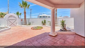 A covered outdoor area with a tiled floor, palm trees, and a gated entrance. - Hacienda Almas Gemelas – Where Luxury Meets the Sea of Cortez (Puerto Peñasco)