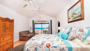 A bedroom with a bed, a wooden wardrobe, a brown leather sofa, a ceiling fan, and a view of the sea through a glass door. - Hacienda Almas Gemelas – Where Luxury Meets the Sea of Cortez (Puerto Peñasco)