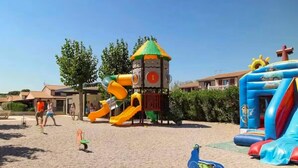Un parque infantil con tobogán, estructura para escalar y un castillo hinchable.