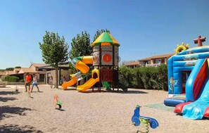 Ein Spielplatz mit Rutsche, Klettergerüst und Hüpfburg.