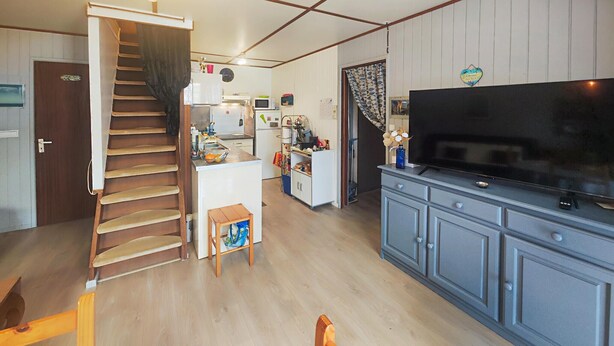 Una cocina con microondas, refrigerador y televisor sobre un mueble.