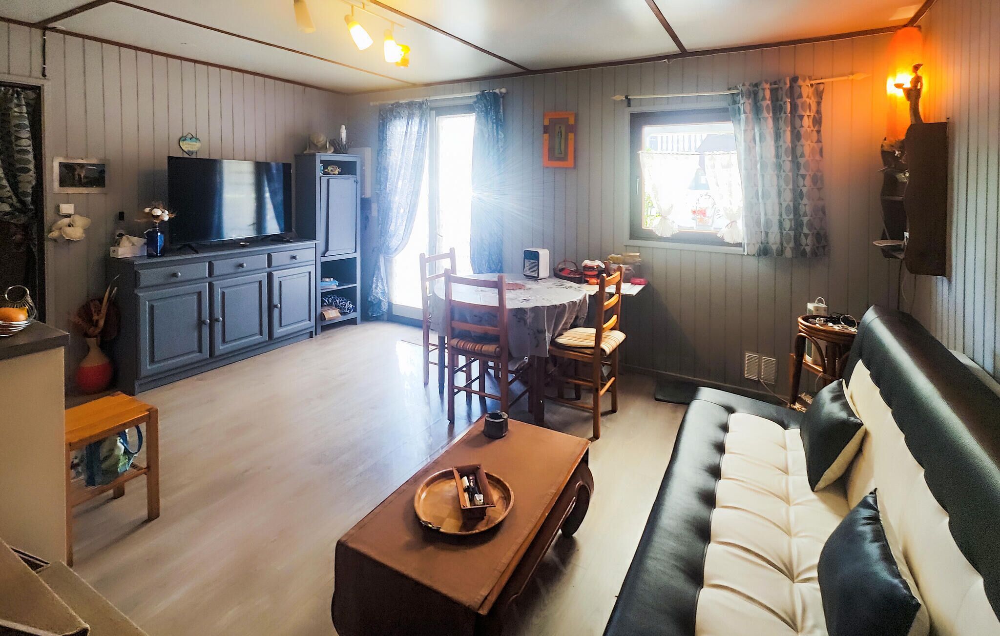 A cozy living room with a sofa, a coffee table, and a dining area with chairs and a table.