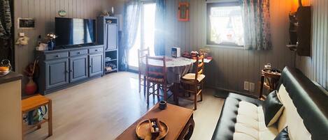 A cozy living room with a sofa, a coffee table, and a dining area with chairs and a table.