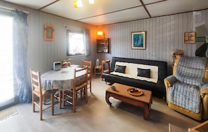 A living room with a sofa, armchair, dining table, chairs, and a coffee table. - MAISON À 500M DE LA PLAGE (Portiragnes)