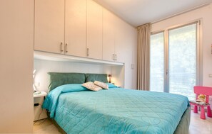 A bedroom with a bed, a nightstand, a lamp, a window with curtains, and a pink chair. - 1 bedroom beautiful apartment in Bogliasco (Bogliasco)