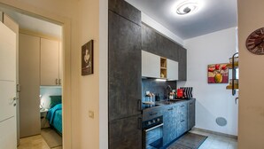 Eine kleine Küche mit dunklen Schränken, einem eingebauten Backofen und einer Arbeitsplatte.