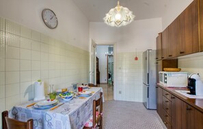 A compact kitchen with a dining table set for four, a refrigerator, and wooden cabinets.